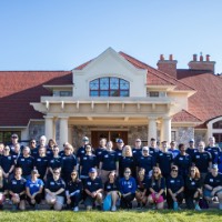 Group of GVSU Alumni Move in day volunteers take a group picture in front of Alumni House and Visitors Center